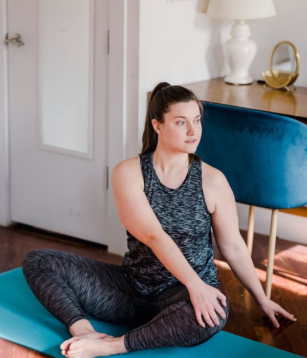 Woman performing a calm, stretching exercise in a dark room with turquoise light.